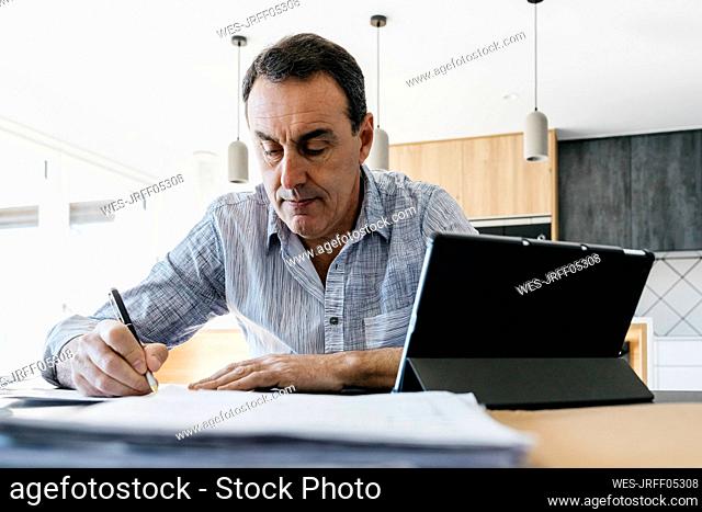 Man writing musical notes sitting at table