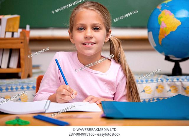 Smiling schoolgirl writing
