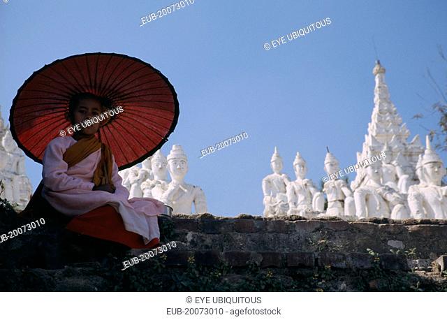 Buddhist Nun sat on a wall with umbrella at Mingun ancient city