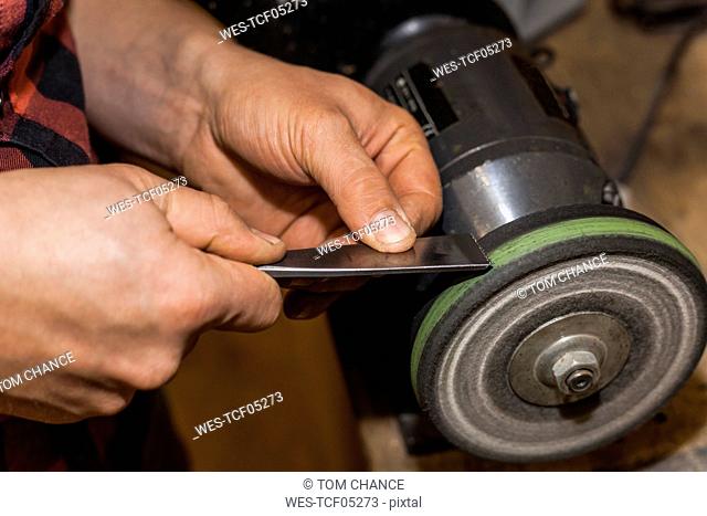 Man sharpening chisel on grinder