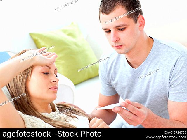 Caring man check the temperature of his sick girlfriend with a thermometer