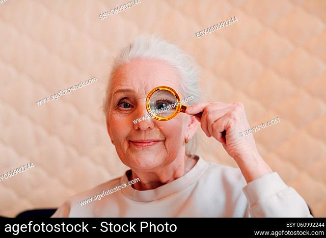 The elderly woman with magnifier loupe in hand