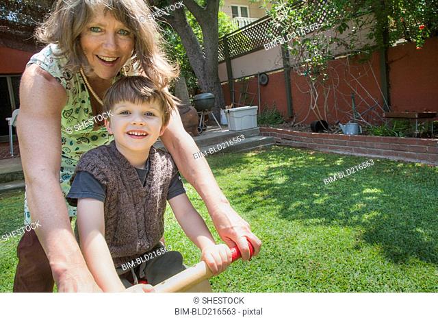 Caucasian grandmother and grandson riding bicycle in backyard