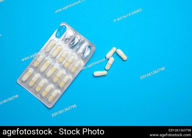 White oval pills and blister pack on a blue background