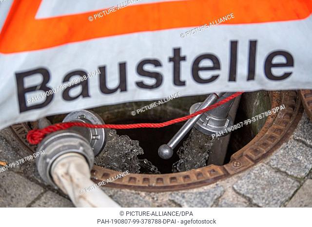 06 August 2019, Bavaria, Munich: Water pumped out of the S-Bahn tunnels flows into a gully cover blocked off by THW. Photo: Lino Mirgeler/dpa