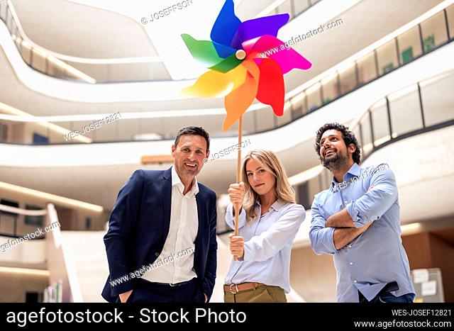Businesswoman holding pinwheel toy by colleagues in lobby