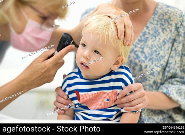 Infant baby boy child being examined by his pediatrician doctor during a standard medical checkup in presence and comfort of his mother