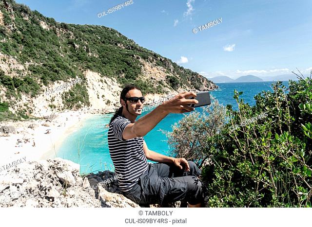 Man taking selfie on cliff top, Lefkada Island, Levkas, Greece