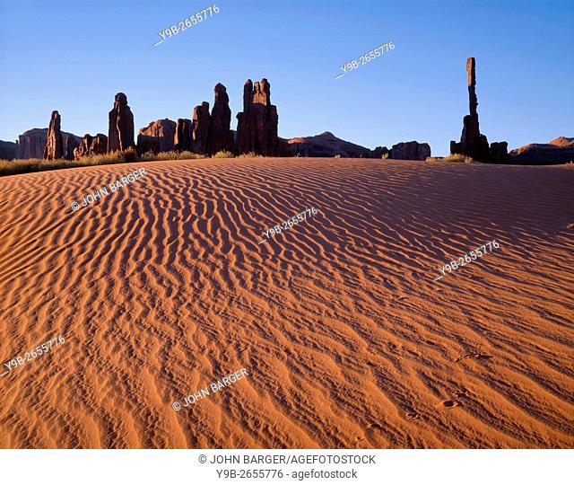 USA, Arizona, Navajo Tribal Park, Sunrise defines texture of sand dunes with rock towers called Yei-Bi-Chei rising in the distance