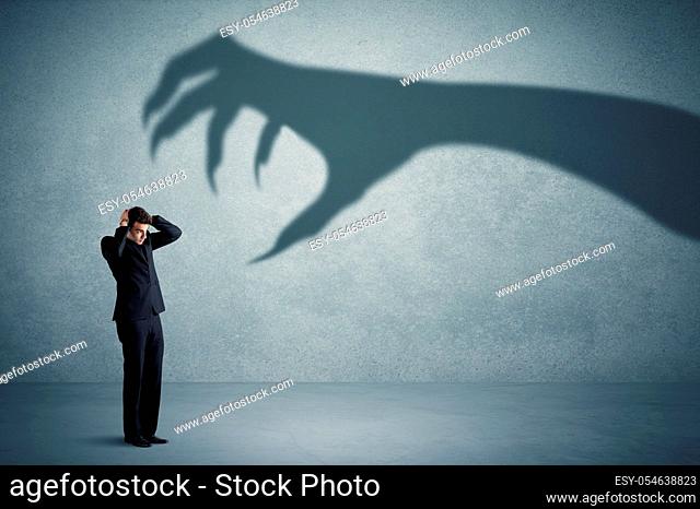 Business person afraid of a big monster claw shadow concept on background