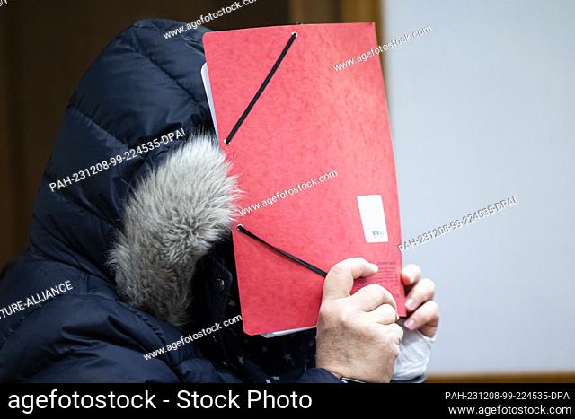 08 December 2023, Lower Saxony, Bückeburg: The defendant enters a courtroom in Bückeburg district court before the start of the trial and holds a folder of...