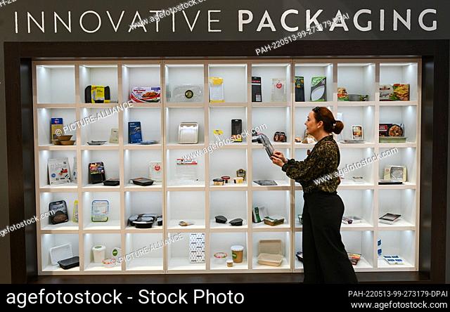 13 May 2022, Hessen, Frankfurt/Main: Claudia Diedrichsen stands by a shelf of sustainable packaging at the Sealpac GmbH Oldenburg stand at the meat industry...