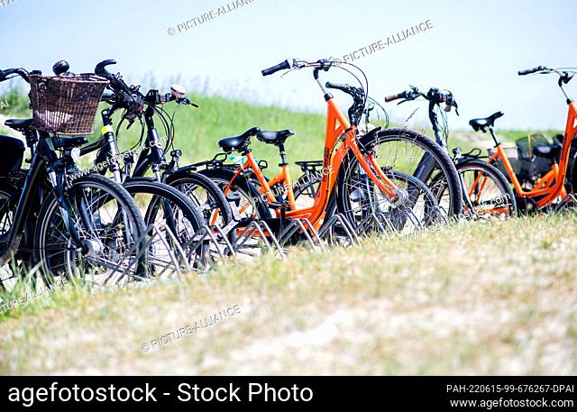 15 June 2022, Lower Saxony, Hooksiel: Numerous bicycles of tourists stand in sunny weather at a bicycle parking lot on the beach