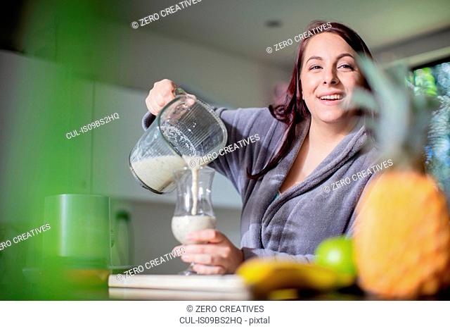 Woman having smoothie for breakfast at home