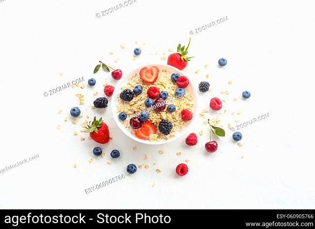 Oatmeal porridge in bowl topped with fresh berries, and homemade crunchy granola