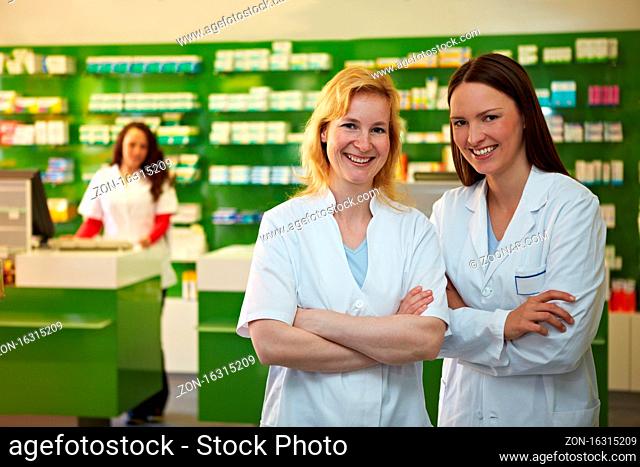 Zwei lachende Apothekerinnen stehen zufrieden in einer Apotheke