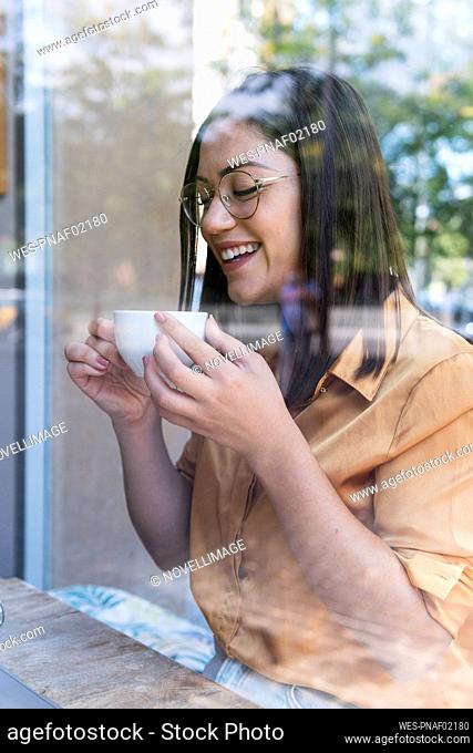 Happy young businesswoman having coffee at cafe