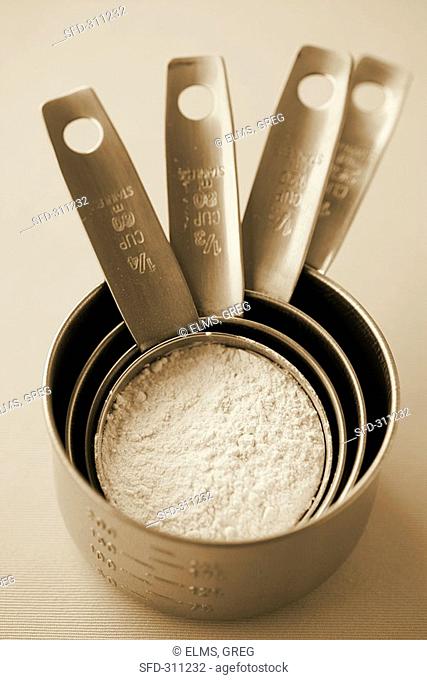 Measuring cups of different sizes with flour