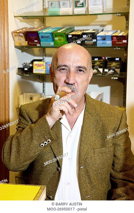 Portrait of mature tobacco store owner smoking cigar