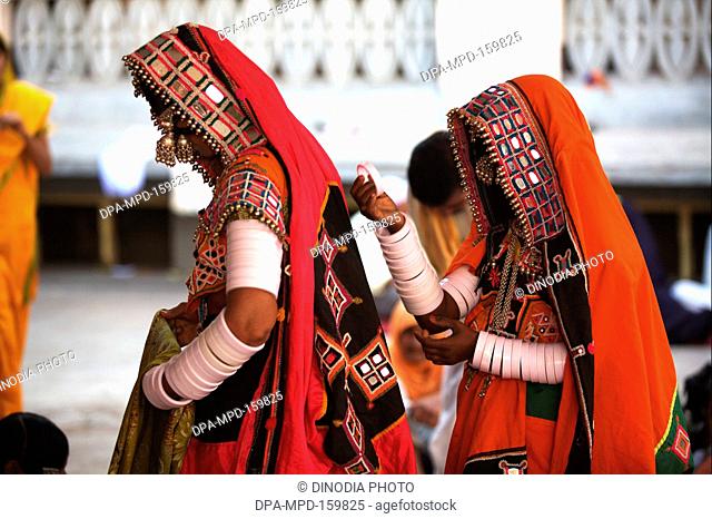 Nomad women dressed in their traditional colourful attire sitting outside the Sachkhand Saheb Gurudwara in Nanded ; Maharashtra ; India