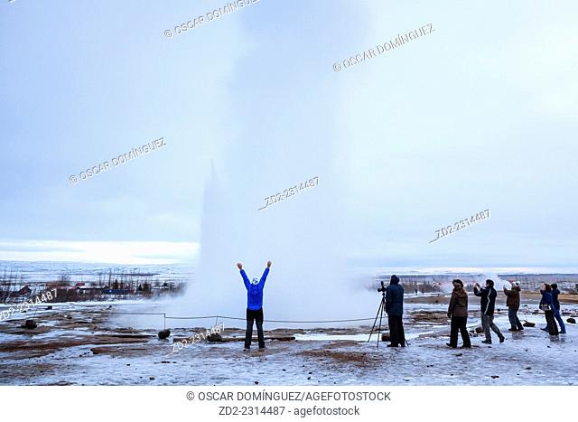 Visitors watching the famous Strokkur geyser wich erupts about every 4–8 minutes. Geysir. Haukadalur. Iceland