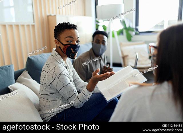 Business people in face masks discussing paperwork in office meeting