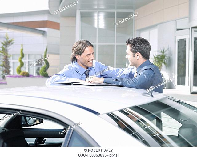 Businessmen talking near car