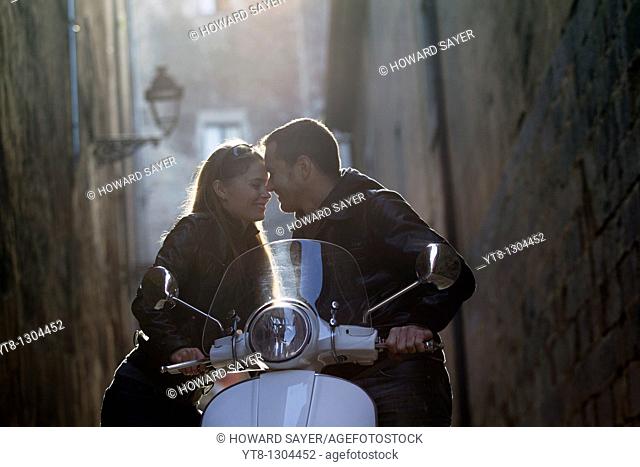 Couple embracing and leaning on a motor scooter