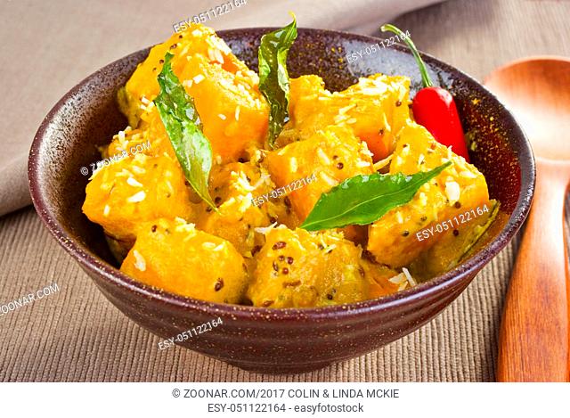 A bowl of chunky pumpkin curry, flavoured with coconut, mustard seeds, cumin, chilli and curry leaves