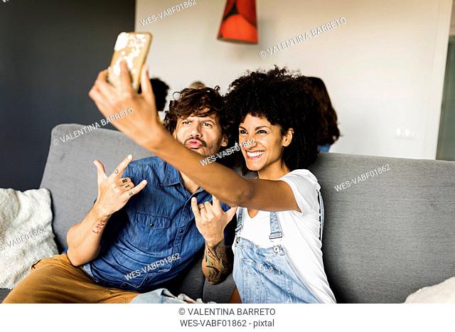 Happy couple sitting on couch taking a selfie