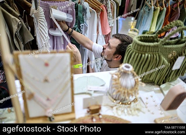 RUSSIA, MOSCOW - APRIL 28, 2023: A staff member is seen amid clothing racks during the Moscow Fashion Week at the Oceania Shopping Centre