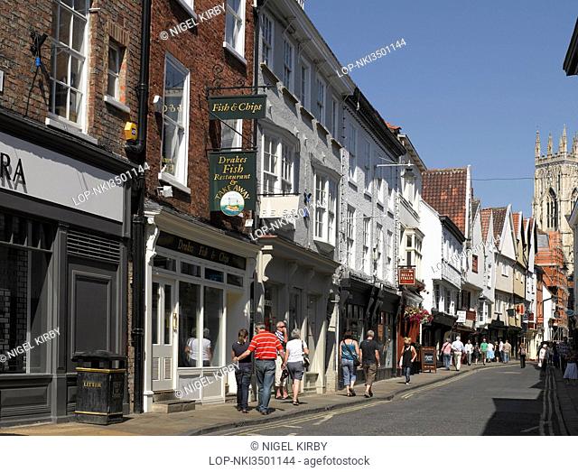 England, North Yorkshire, York. Shops and restaurants in Low Petergate and the West Tower of York Minster