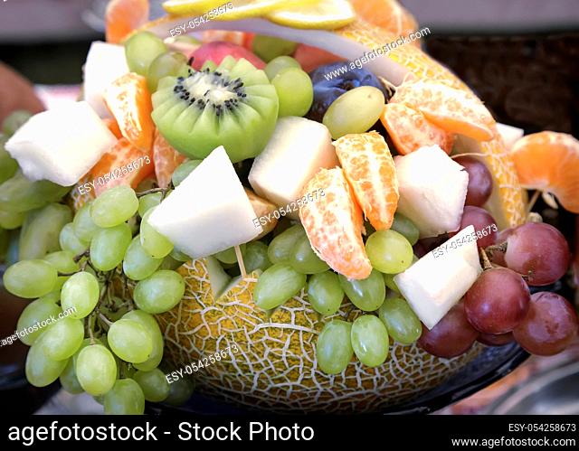 Big pumpkin, decorated in the form of a basket and filled with a variety of fruit: grapes, kiwi, bananas, tangerines