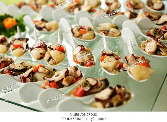 Seafood served on porcelain spoons and glass table