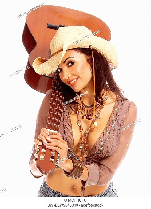 young, dark haired woman in jeans and cowboyhat with a guitar on her shoulder