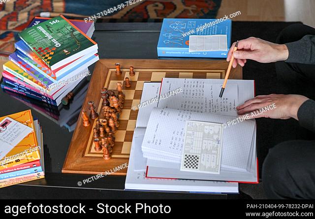 01 April 2021, Berlin: Surrounded by chess books in his apartment, the chess player Heiermann has written his next move on a postcard in correspondence chess