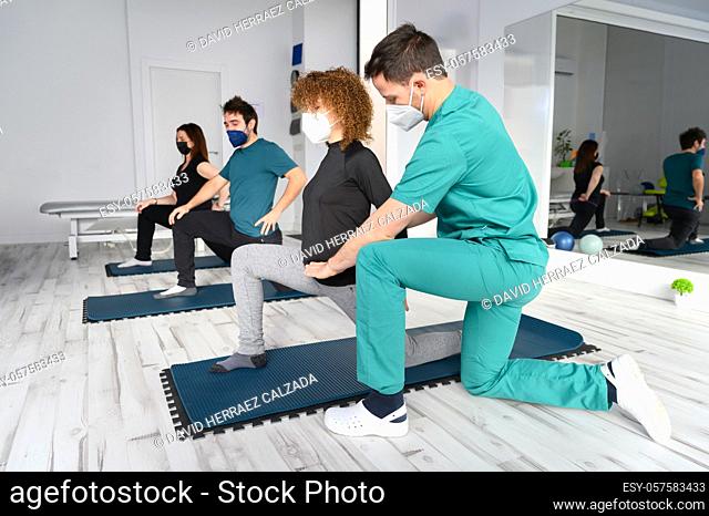Group of persons on yoga mats assisted by physiotherapist at the rehabilitation clinic. High quality photo