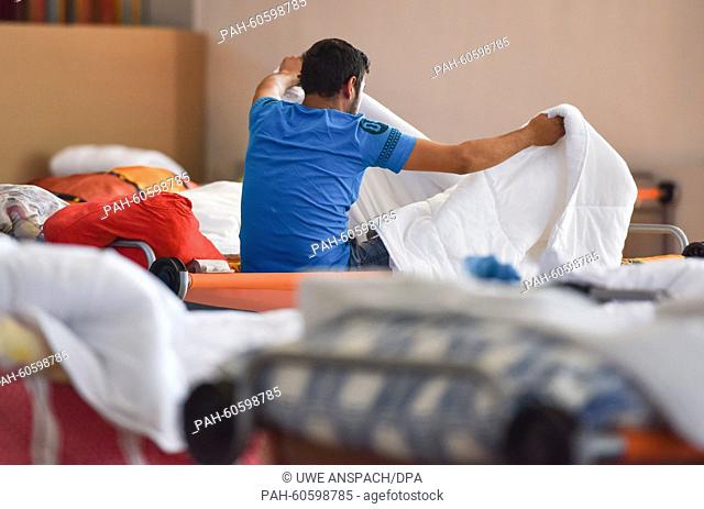 A refugee sits on a camp bed at the Patrick-Henry-Village refugee accommodation centre in Heidelberg, Germany, 6 August 2015