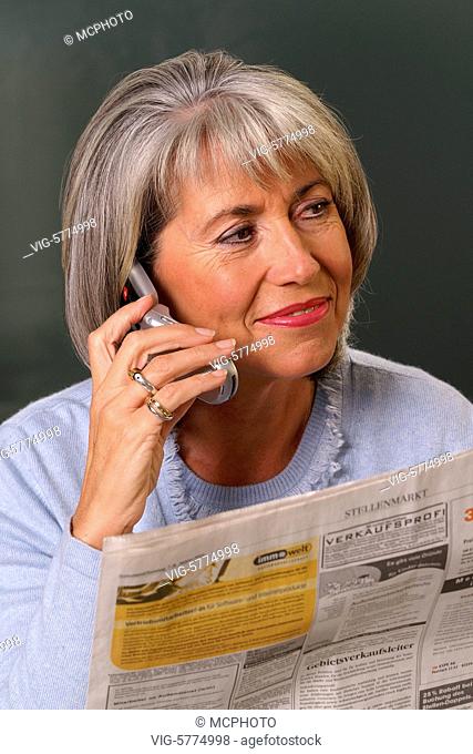 Eine aeltere Frau liest die Stellenangebote in der Tageszeitung und telefoniert, Hamburg 2006 - Hamburg, Germany, 16/01/2006