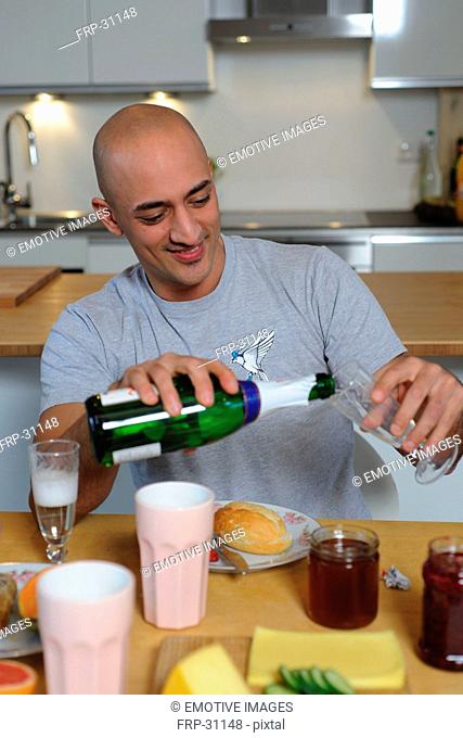 Man in kitchen pouring champagne into glass
