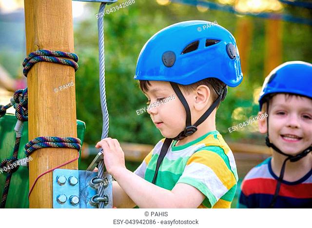 Happy children having fun in adventure park. Two adventurous healthy preschool boys, twin brothers enjoying active day outdoors climbing on the trees