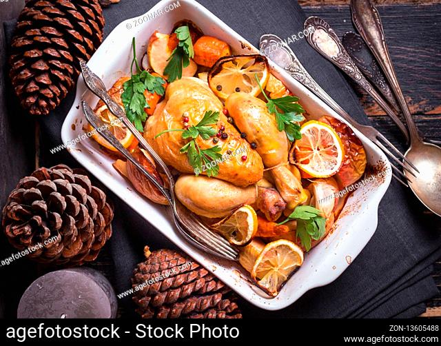 Roasted chicken. Christmas food. Rustic celebration table with roasted chicken, vegetables, apples, decorated with candles, vintage cutlery