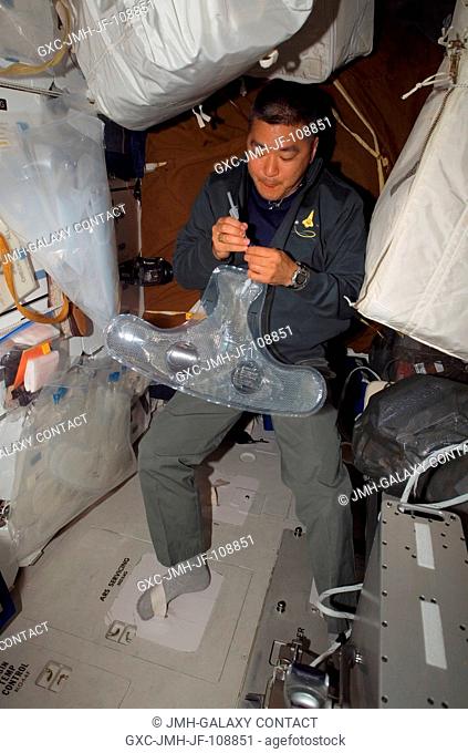 Astronaut Daniel Tani, STS-120 mission specialist, works with an Extravehicular Mobility Unit (EMU) spacesuit water bag on the middeck of Space Shuttle...