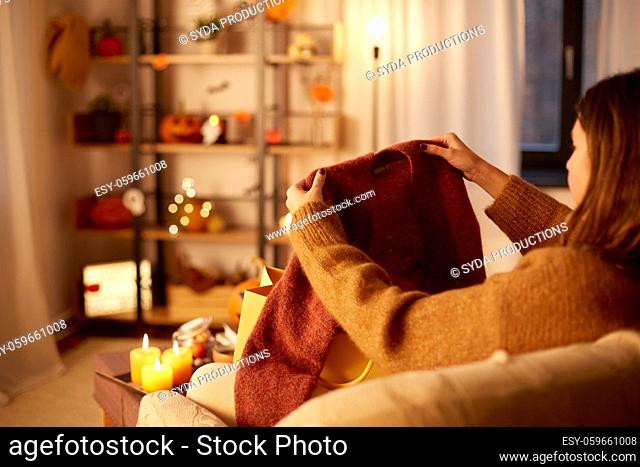 woman taking cardigan from shopping bag at home