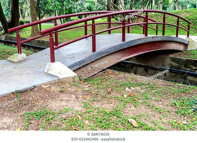 Small bridge with red iron railing in the park