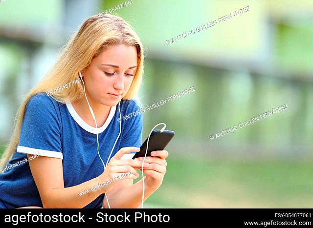 Serious teenage girl listening to music checks phone