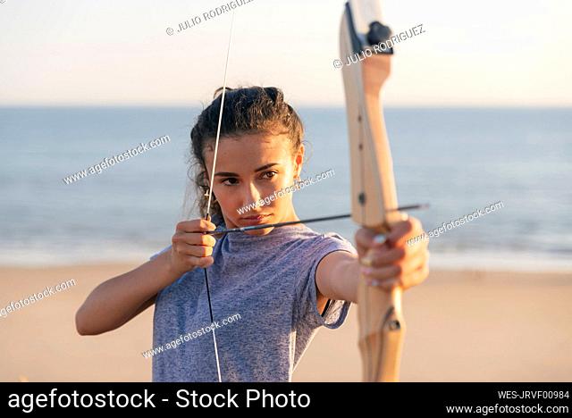 Young woman practicing archery at beach