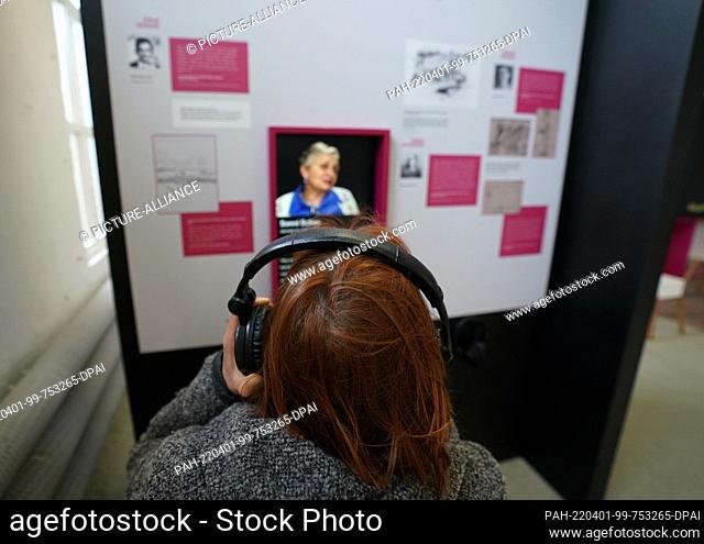 31 March 2022, Hamburg: An employee sits with headphones in front of a multimedia wall in the exhibition ""Children in Bergen-Belsen Concentration Camp"" at the...