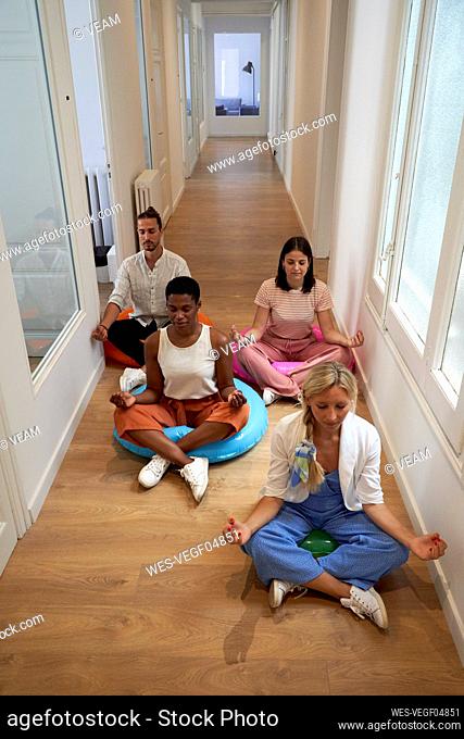 Business team practicing yoga while sitting on floor