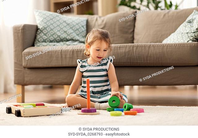 happy baby girl playing with toy blocks at home